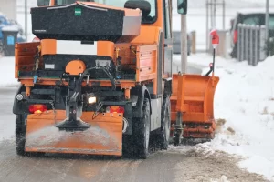 A snow plow clearing the road and spreading salt.